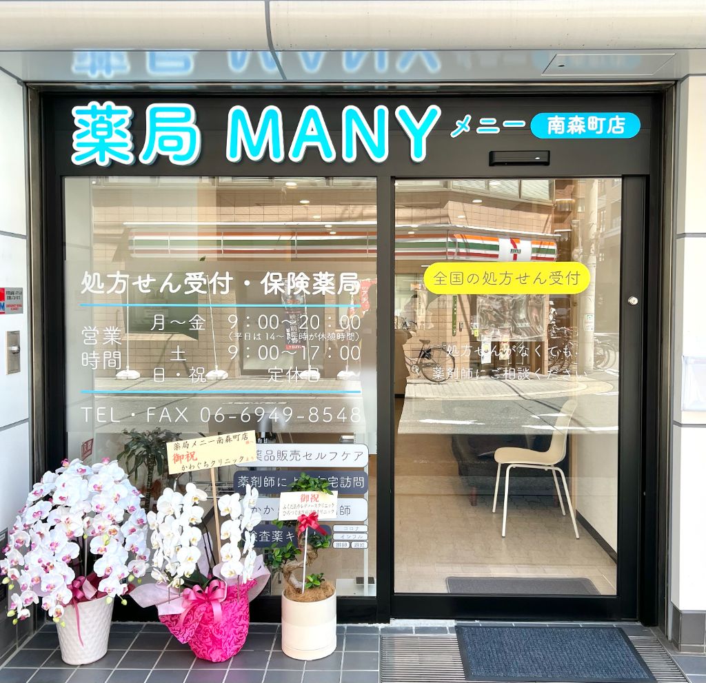 水色の薬局MANY 南森町店の看板とガラス張りの入口の外観